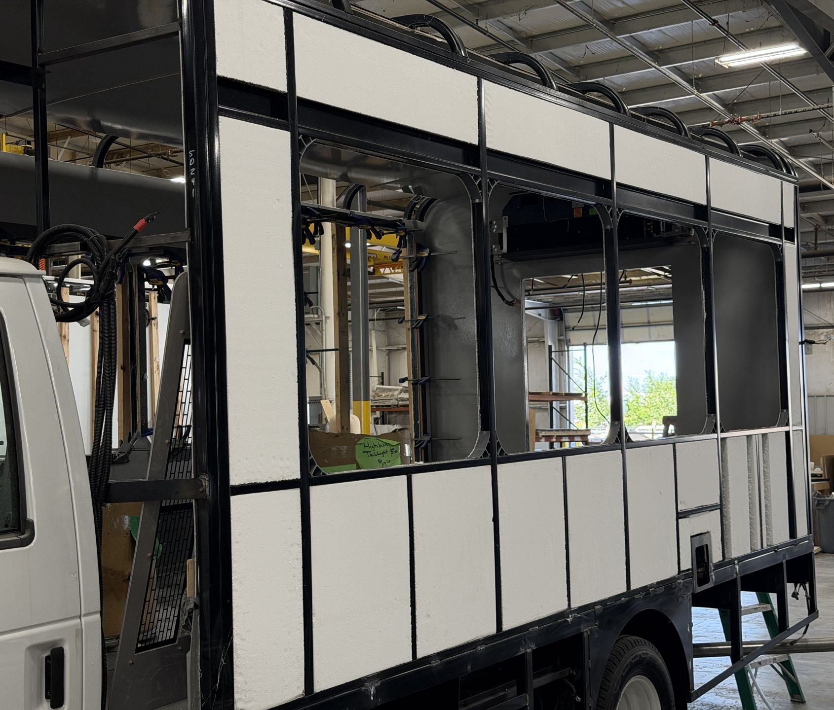 Fully welded, powder-coated steel shuttle bus cage on the chassis with cut-to-fit foam insulation, on the HLE factory floor