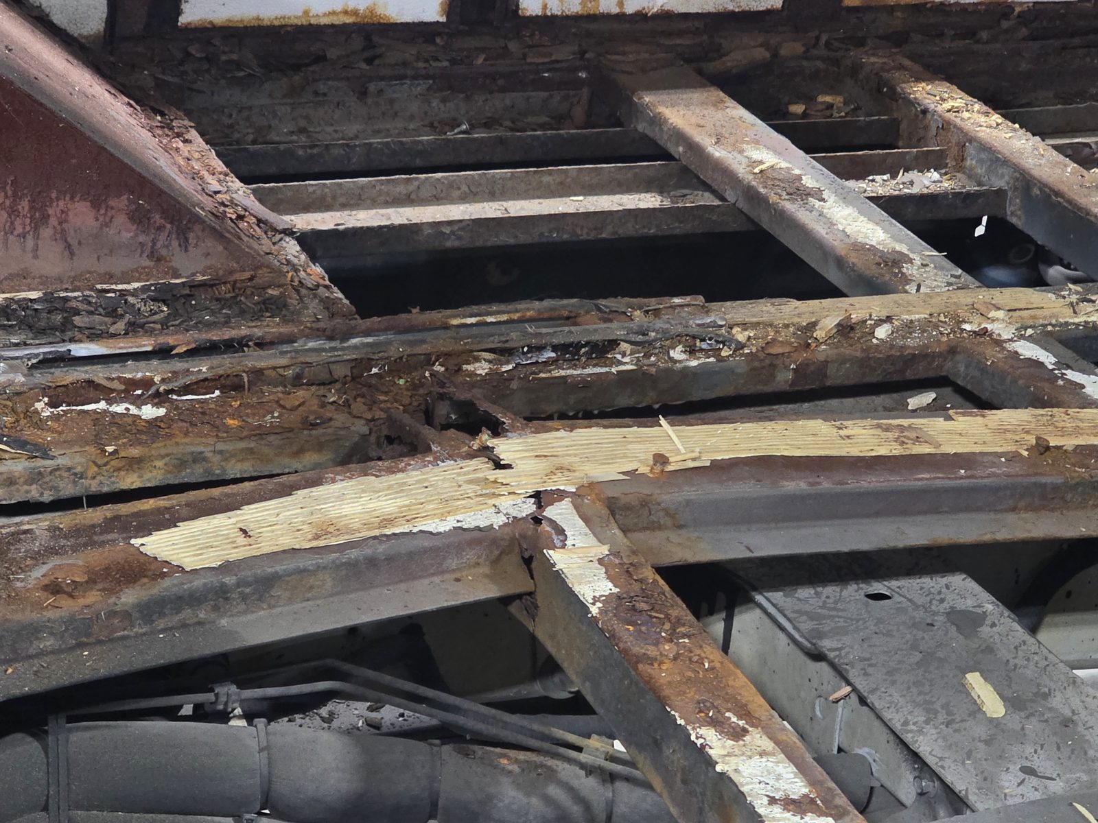 Rotted plywood floor decking over rusted steel floor structure, exposed during teardown